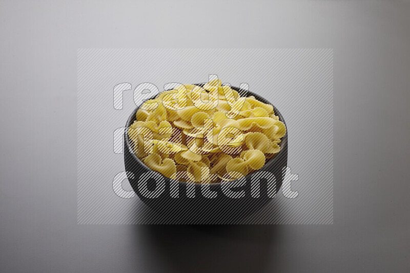 Fiocchi pasta in a pottery bowl on grey background