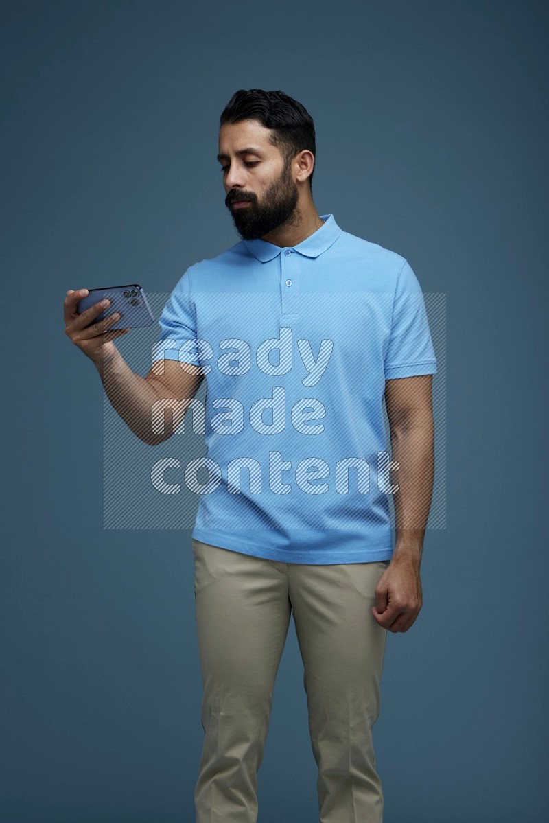 A man Watching a movie on his phone in a blue background wearing a Blue shirt
