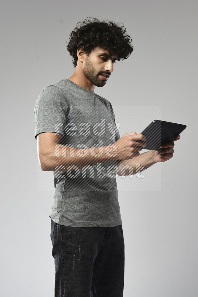 A man wearing casual standing and gaming on a tablet on white background