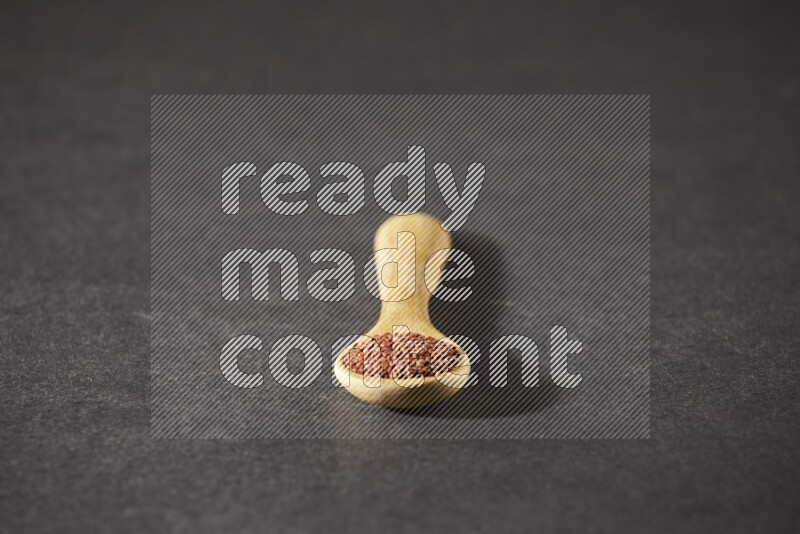 ملعقة خشبية ممتلئة ببذور حب الرشاد علي خلفية سوداء