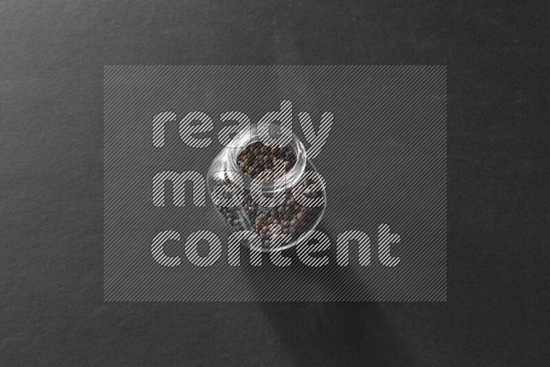 فلفل أسود في وعاء زجاجي علي خلفية سوداء