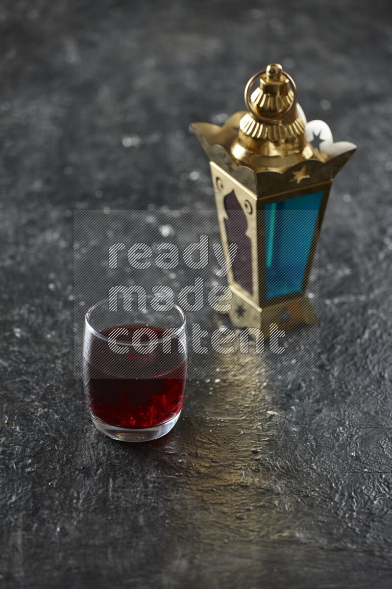 A golden lantern with different drinks, dates, nuts, prayer beads and quran on textured black background