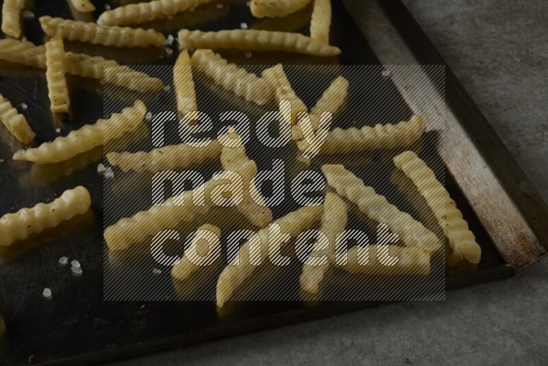 crinkle fries in a black stainless steel rectangle tray on grey textured counter top