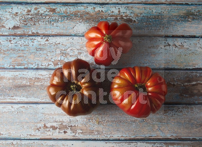 three heirloom tomatoes topview on a textured vinyl background
