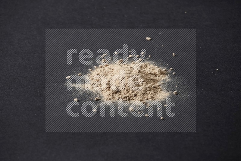 A small pile of garlic powder on a black background