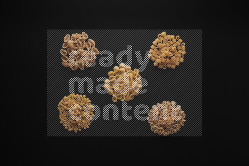 Different pasta types in bunches on black background