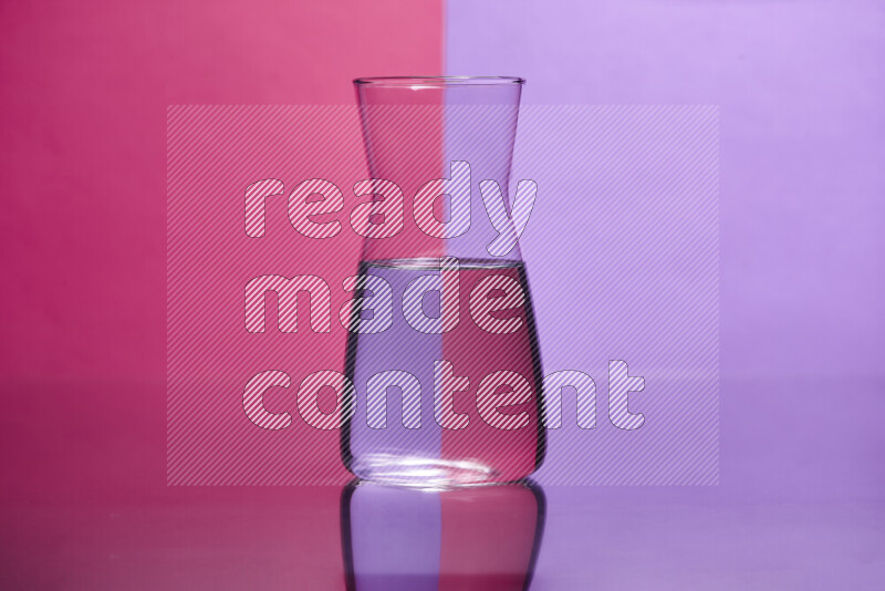 The image features a clear glassware filled with water, set against pink and light purple background