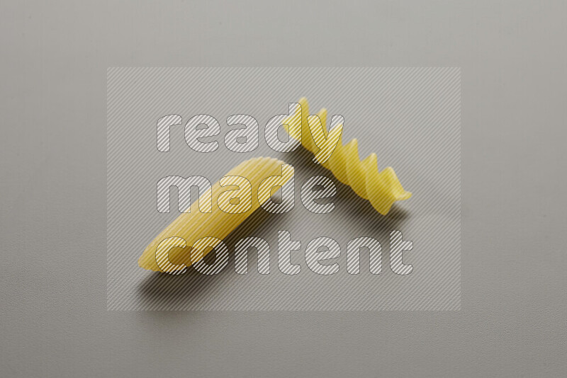 Penne pasta with other types of pasta on grey background