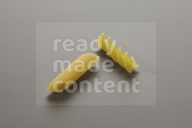 Penne pasta with other types of pasta on grey background