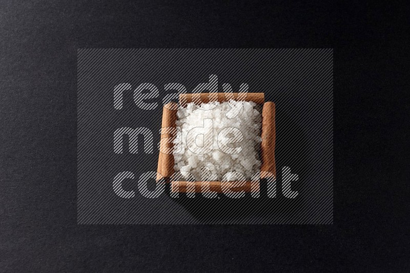 A single square of cinnamon sticks full of salt on black flooring