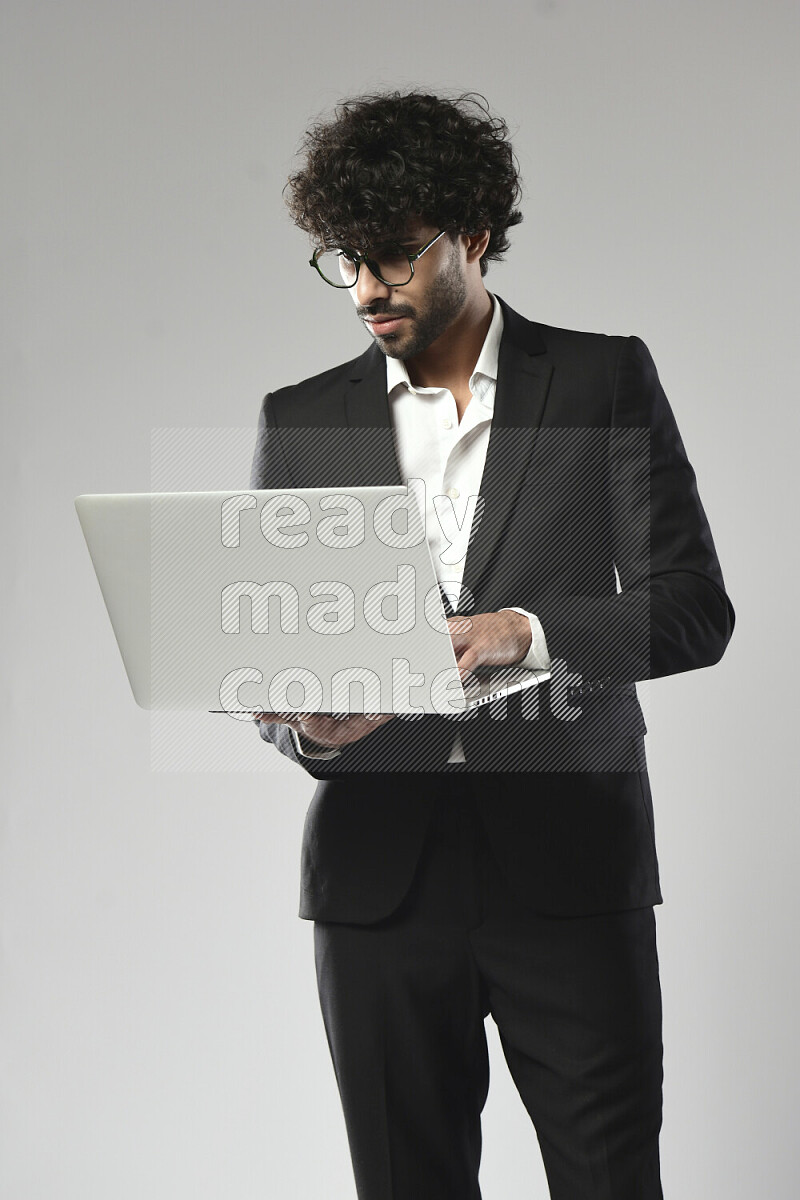 A man wearing formal standing and working on a laptop on white background