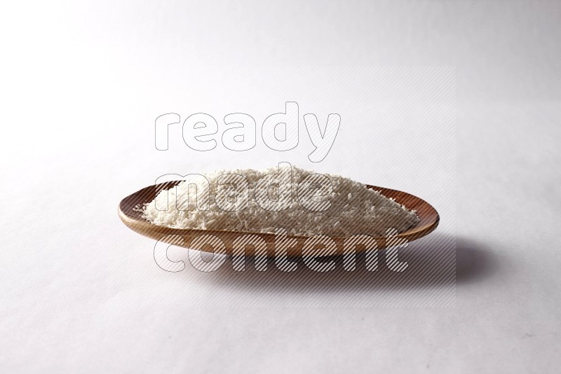 Desiccated coconuts in a wooden plate on white background