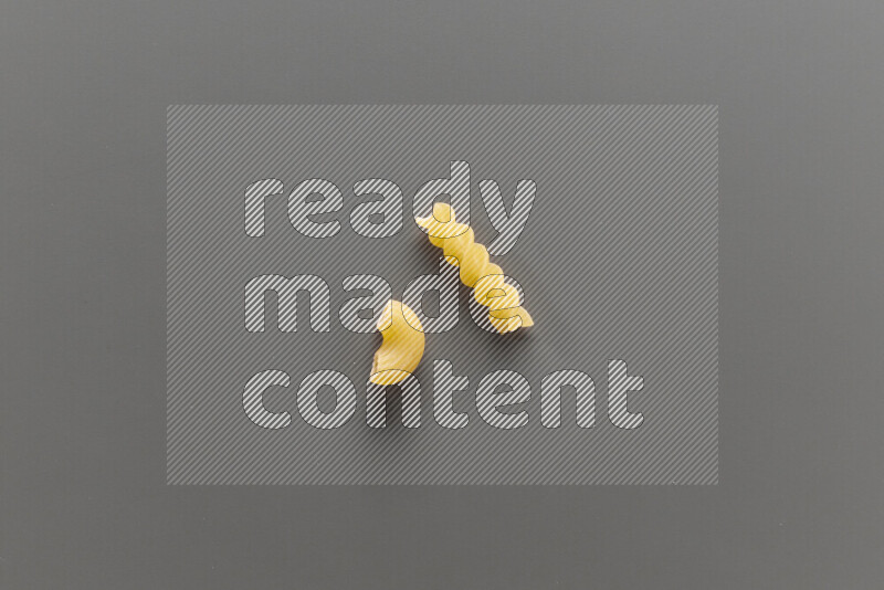 Elbow pasta with other types of pasta on grey background