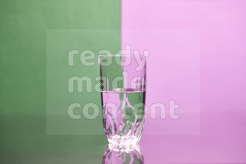 The image features a clear glassware filled with water, set against green and light purple background