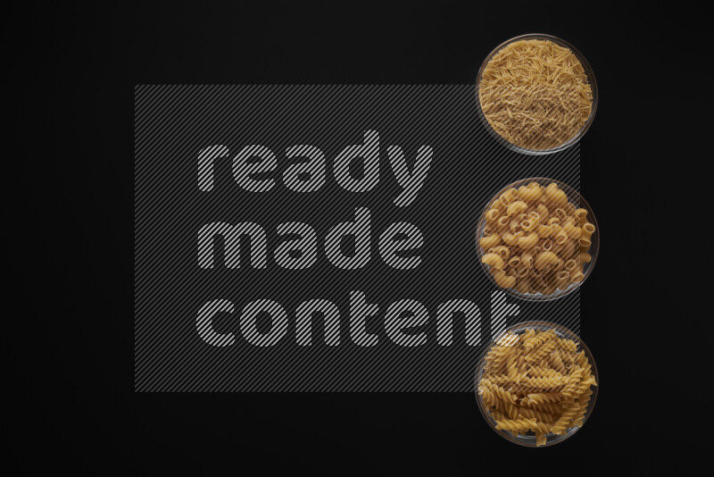 Different pasta types in 3 glass bowls on black background
