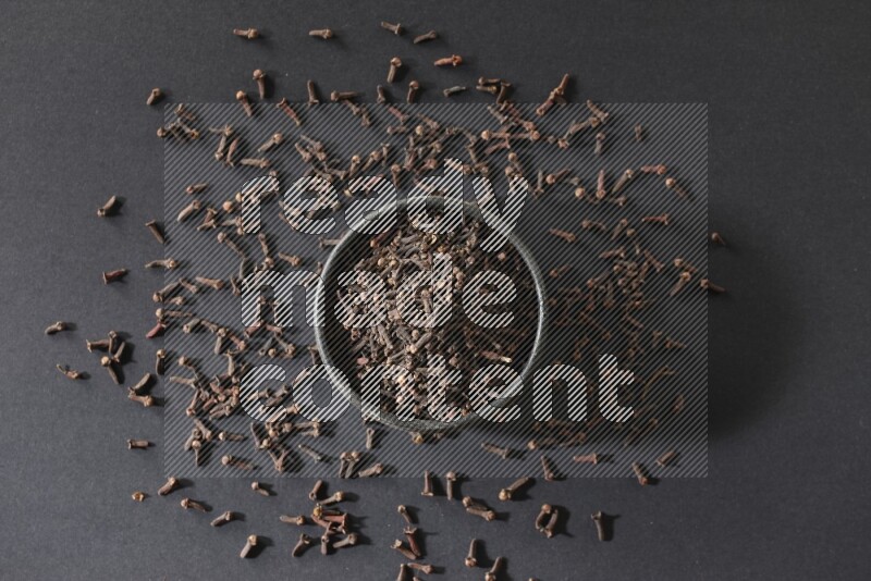 وعاء فخاري أسود ممتلئ بحبوب القرنفل علي خلفية سوداء