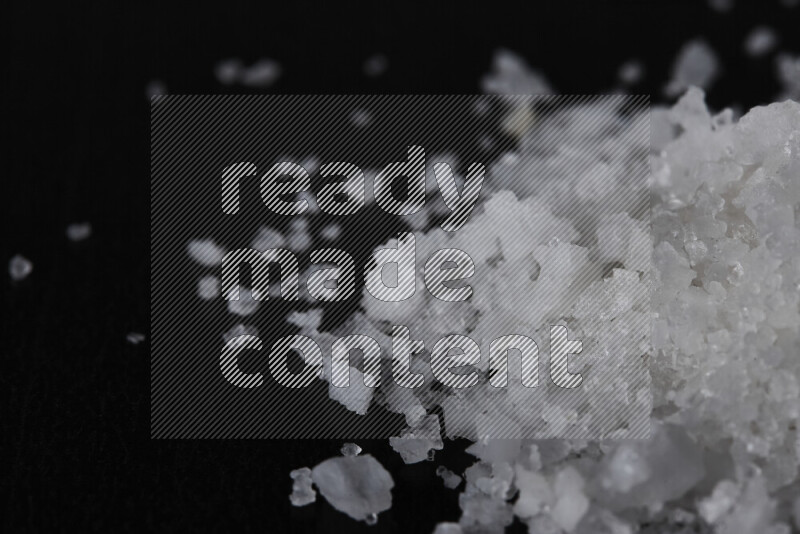 A bunch of coarse sea salt crystals on black background