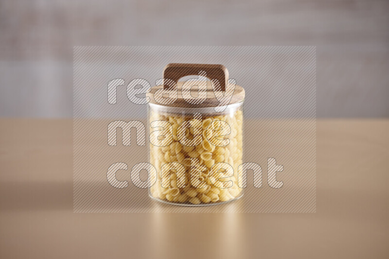 Raw pasta in glass jars on beige background