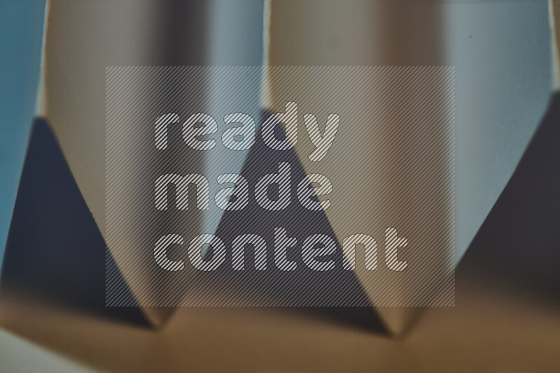 صورة مجردة مقربة تظهر طيات ورقية هندسية حادة بتدرجات اللون الأزرق مع درجات لونية دافئة