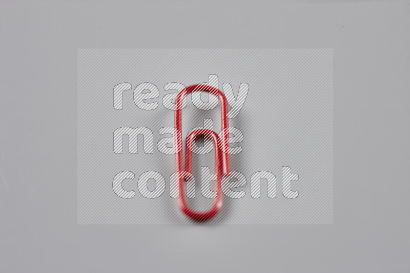 Red paper clips isolated on a grey background