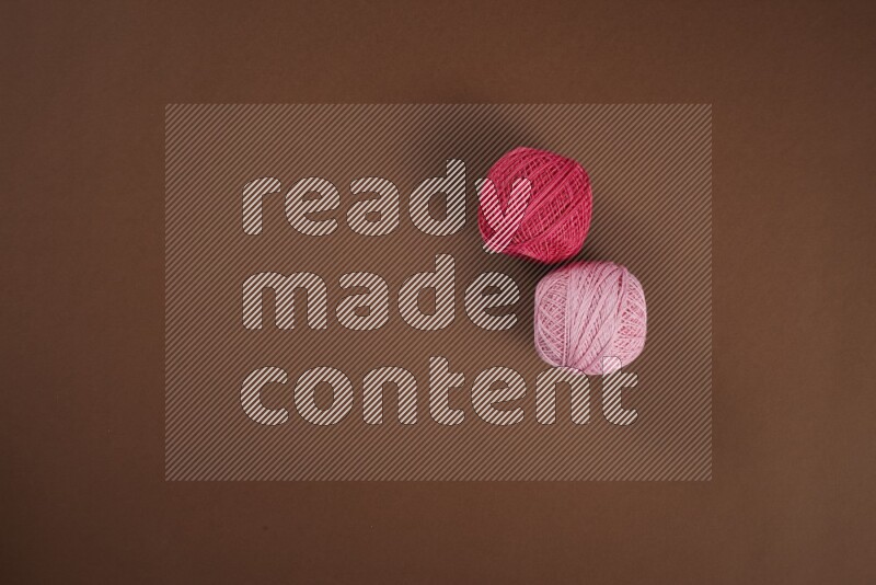 A pink collection of sewing and tailoring tools arranged on a brown background