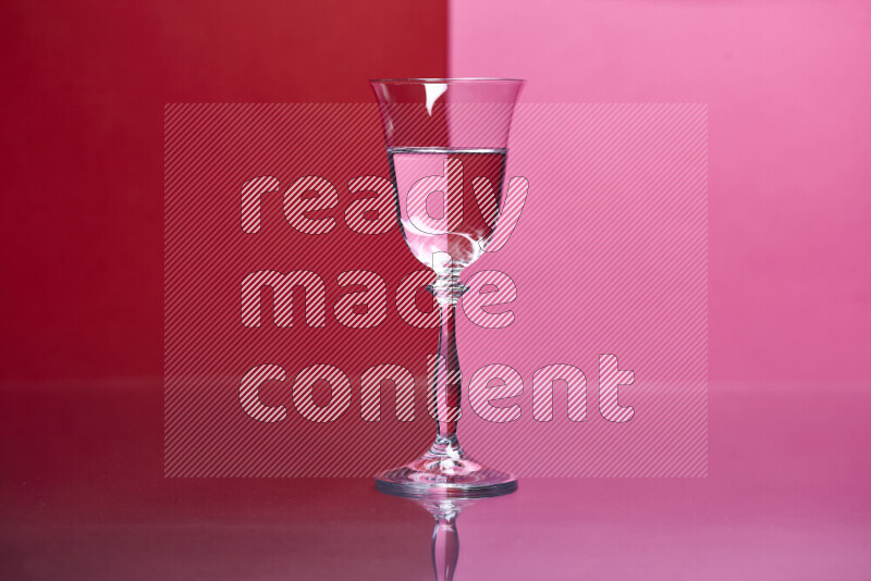 The image features a clear glassware filled with water, set against red and pink background