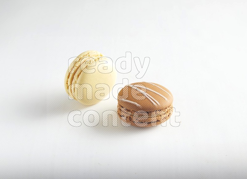 45º Shot of of two assorted Brown Irish Cream, and Yellow Vanilla macarons on white background