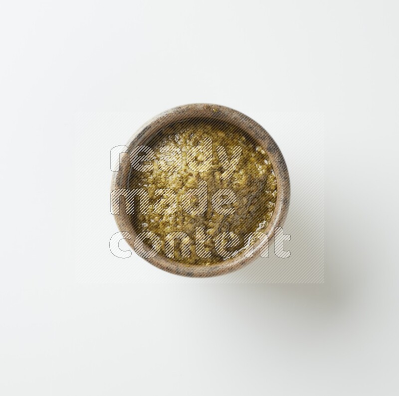 medium multi color pottery round bowl filled with pesto paste on a white counter top