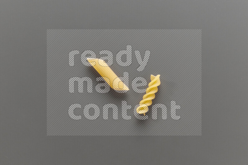 Penne pasta with other types of pasta on grey background