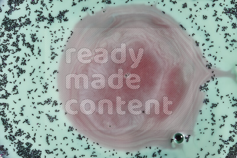 لقطة مقرّبة لدوامات من اللون الأحمر مع بريق أرجواني متلألئ منتشر على خلفية من اللون الأخضر