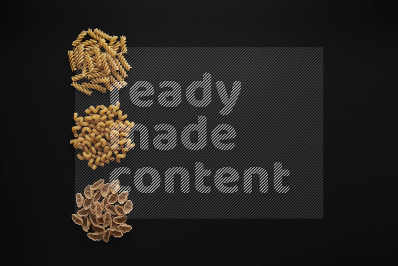 Different pasta types in 3 bunches on black background