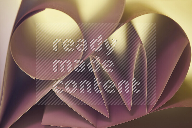 An artistic display of paper folds creating a harmonious blend of geometric shapes, highlighted by soft lighting in pink and warm tones