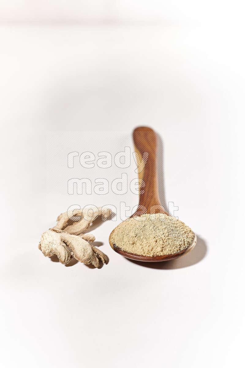 A wooden ladle full of ground ginger powder on white background