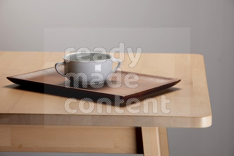 white bowl placed on a rectangular wooden tray on the edge of wooden table