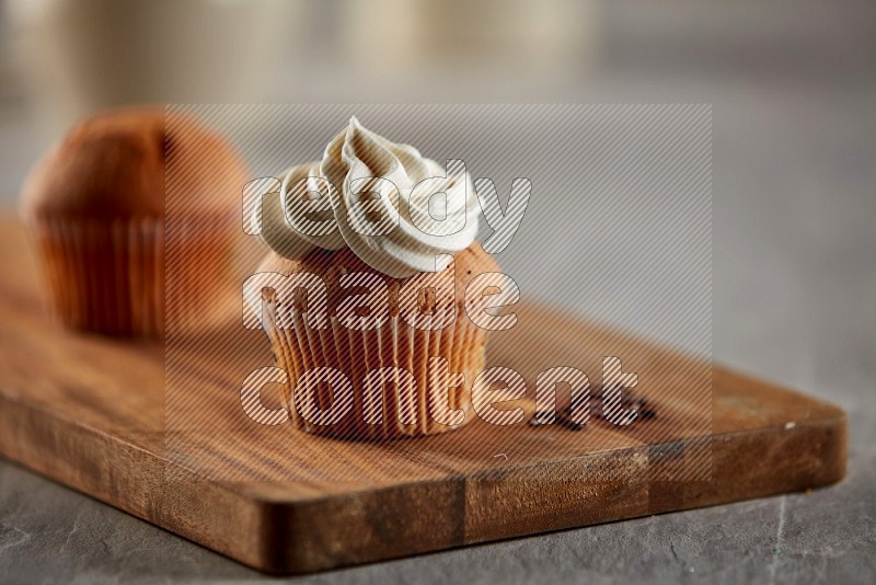 Vanilla cupcake topped with cream on a wooden board