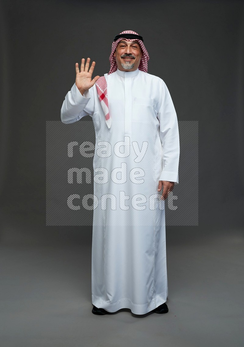 Saudi man with shomag Standing Interacting with the camera on gray background