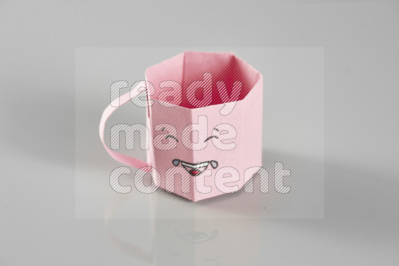 Origami cup on grey background