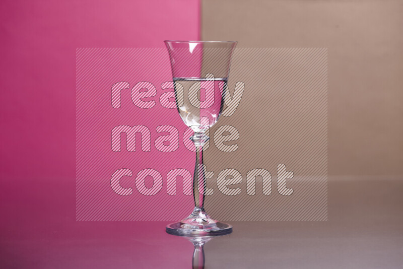 The image features a clear glassware filled with water, set against pink and beige background