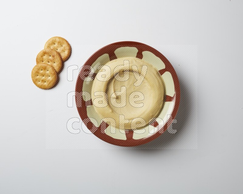 Plain hummus in a traditional plate on a white background