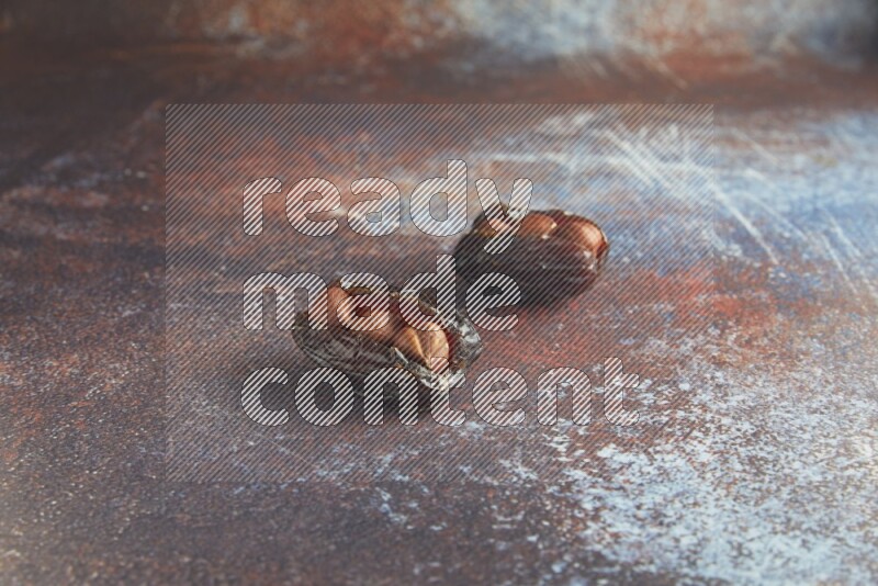 two hazelnut stuffed madjoul dates on a rustic reddish background