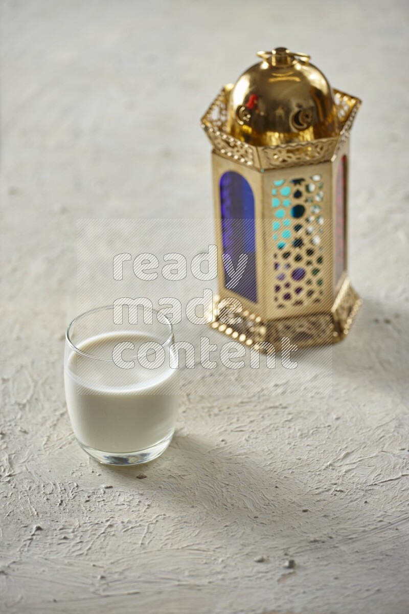 A golden lantern with different drinks, dates, nuts, prayer beads and quran on textured white background