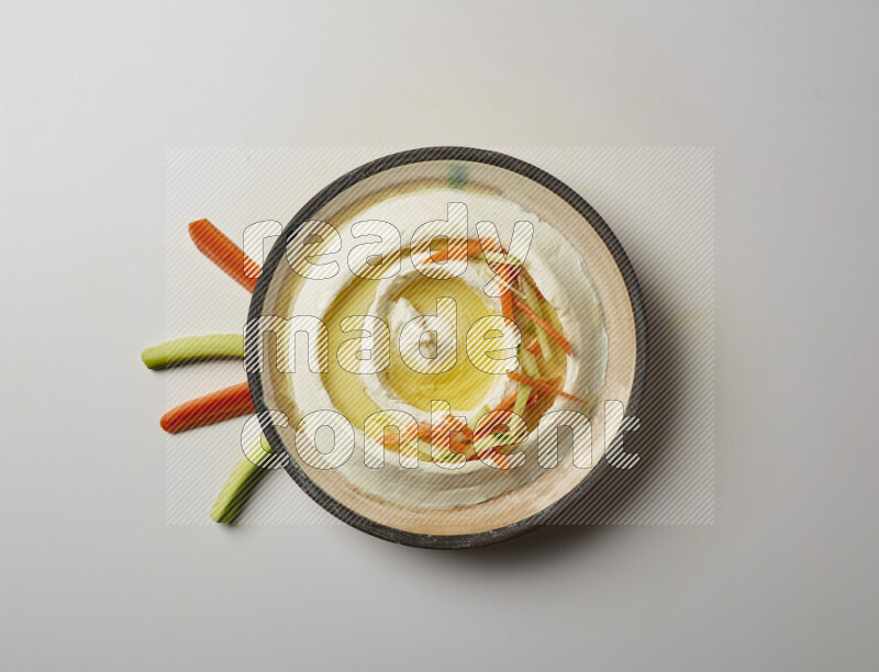 Lebnah garnished with sliced carrots &cucumber in a pottery plate on a white background