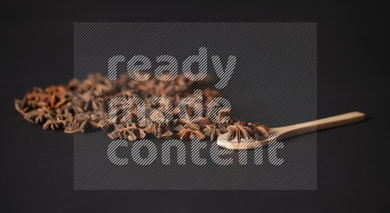 اليانسون النجمي في ملعقة خشبية ومتناثر على أرضية سوداء