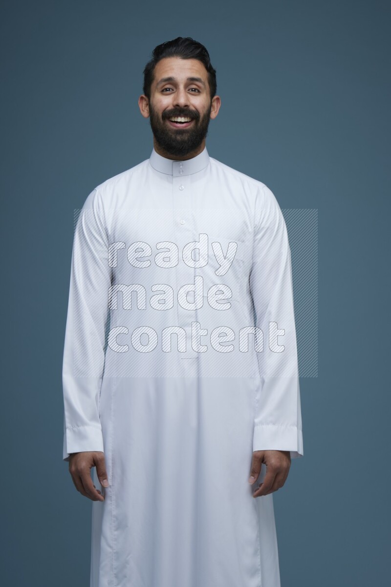 A man posing in a blue background wearing Saudi Thob