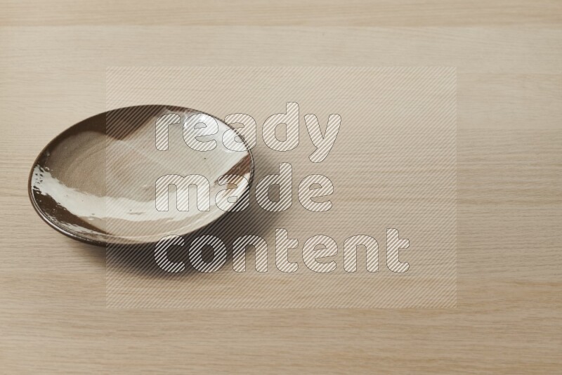 A multicolored pottery plate on light wooden background