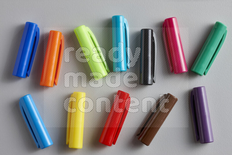 لقطة مقربة لأغطية أقلام ملونة مبعثرة على خلفية رمادية