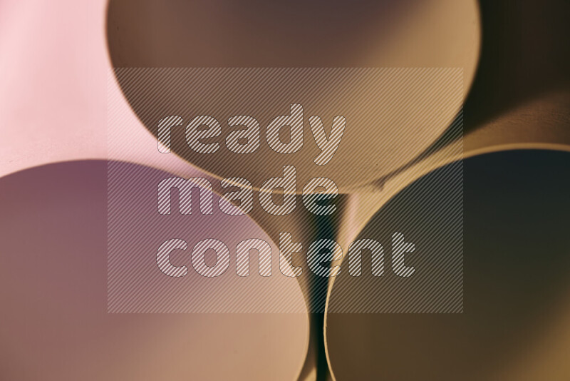 الصورة تعرض فن ورقي تجريدي بأشكال دائرية بدرجات متنوعة من اللون الوردي والدرجات الدافئة