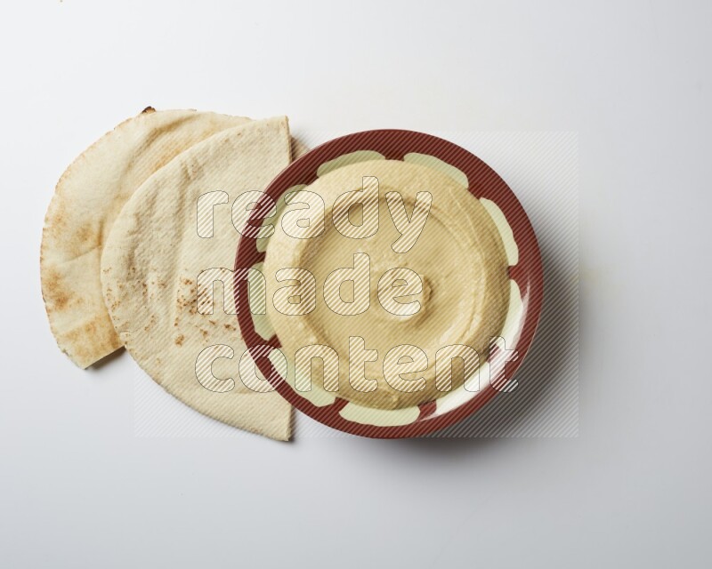 Plain hummus in a traditional plate on a white background