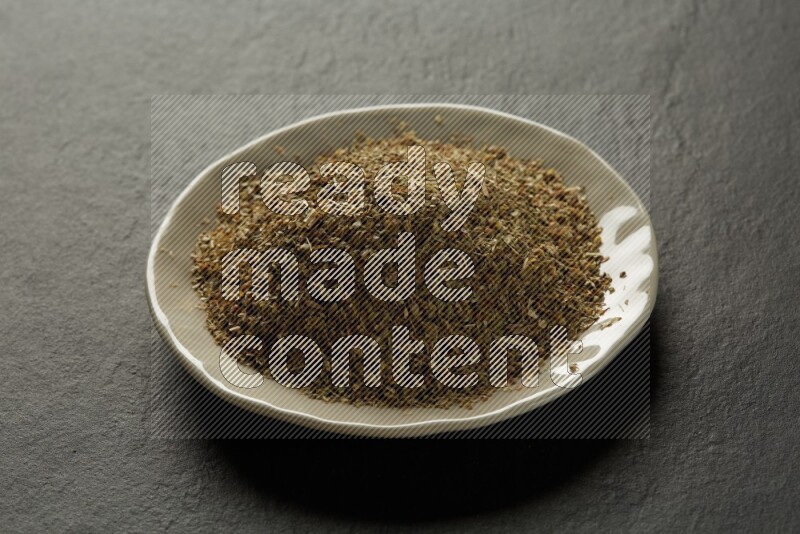 white ceramic round sauce dish filled with herbs on grey textured countertop