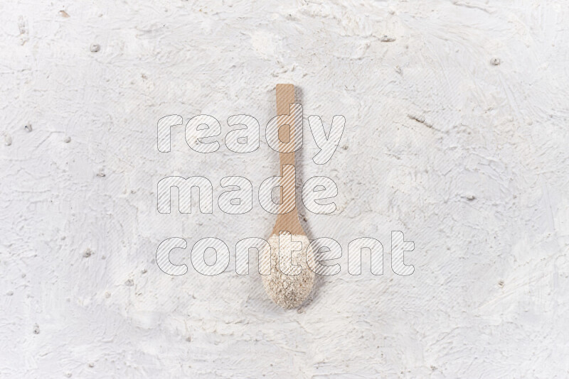 A wooden spoon full of onion powder on white background